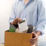 Persona empaquetando objetos personales de escritorio en una caja de cartón tras una desvinculación laboral, con una calculadora visible, representando el impacto de la automatización IA Chile en profesiones administrativas.